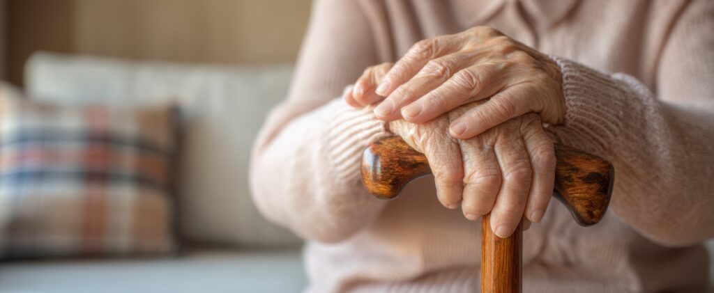 高齡者雙手緊握拐杖，象徵失智症患者在生活中對支撐與陪伴的需求