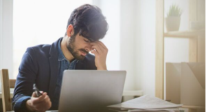 一位年輕男性在電腦前揉眼睛，感到視覺疲勞與不適，象徵用眼過度與需要保護眼睛。