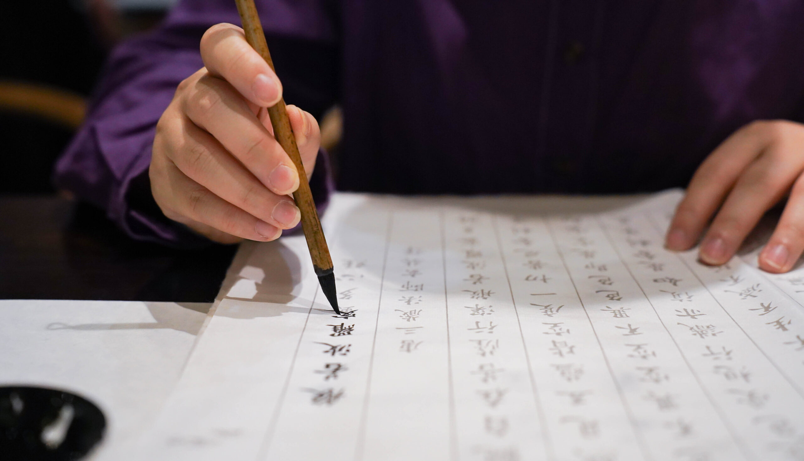 手握毛筆專心書寫書法，展現靜心與專注的書寫狀態