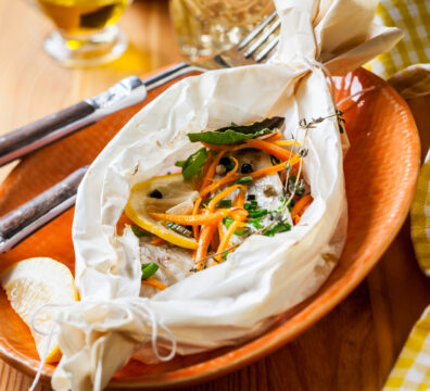 紙包魚製作過程,將魚與櫛瓜、紅蘿蔔與番茄放入料理紙中準備烘烤