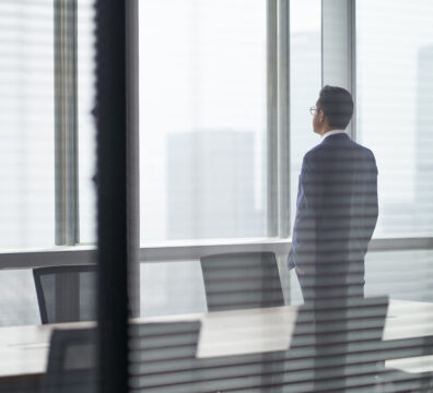 中年職場人士站在辦公室窗前，看著遠方思考離職選擇與職涯轉換