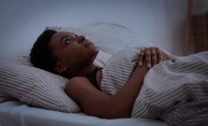 女性半夜躺在床上難以入睡,呈現長期睡眠不足與失眠困擾。
